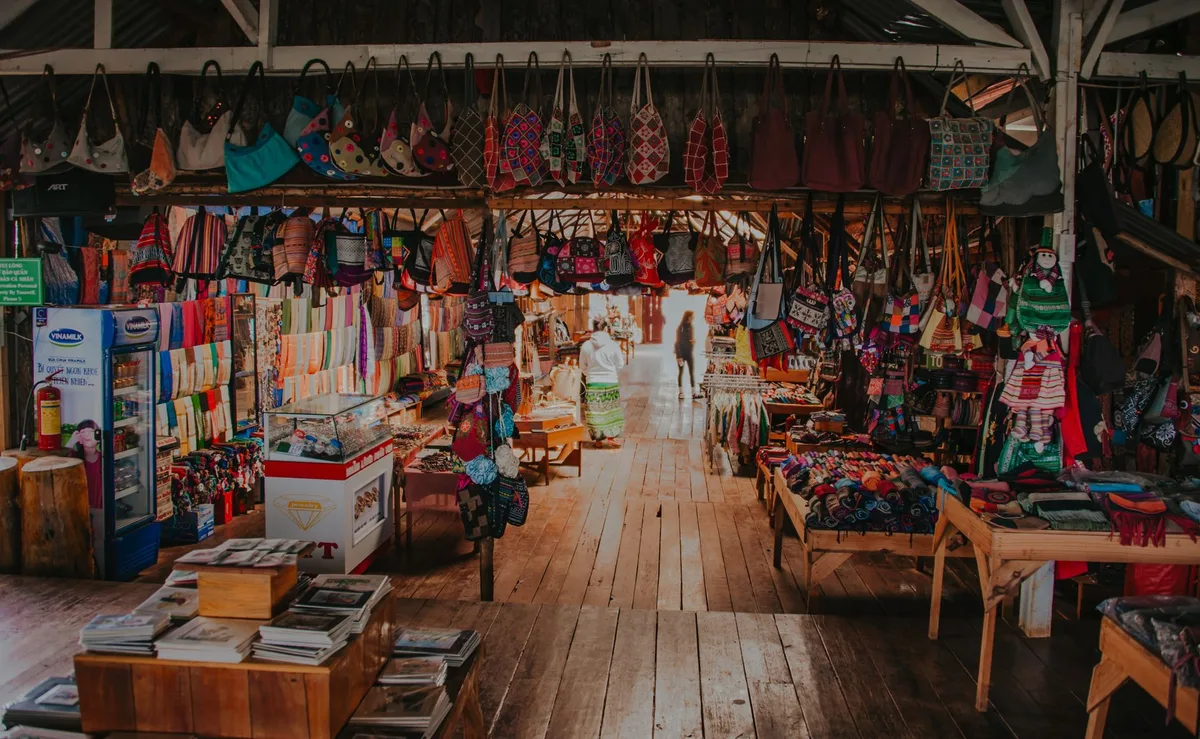 A garage sale setup with various household items and clothing displayed on tables outside a home.
