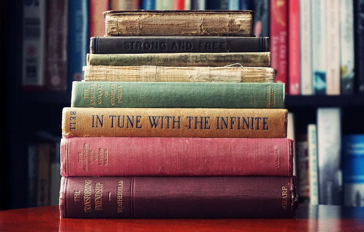 Stack of vintage cookbooks with worn covers showing different decades of recipe collections