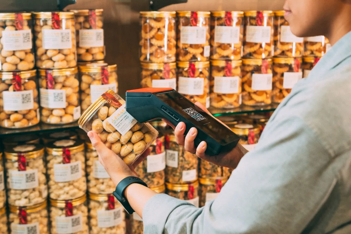 Hand holding smartphone scanning a QR code label on storage inventory