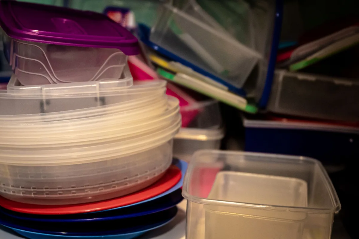 Clear plastic storage bins filled with organized clothing inventory on closet shelves