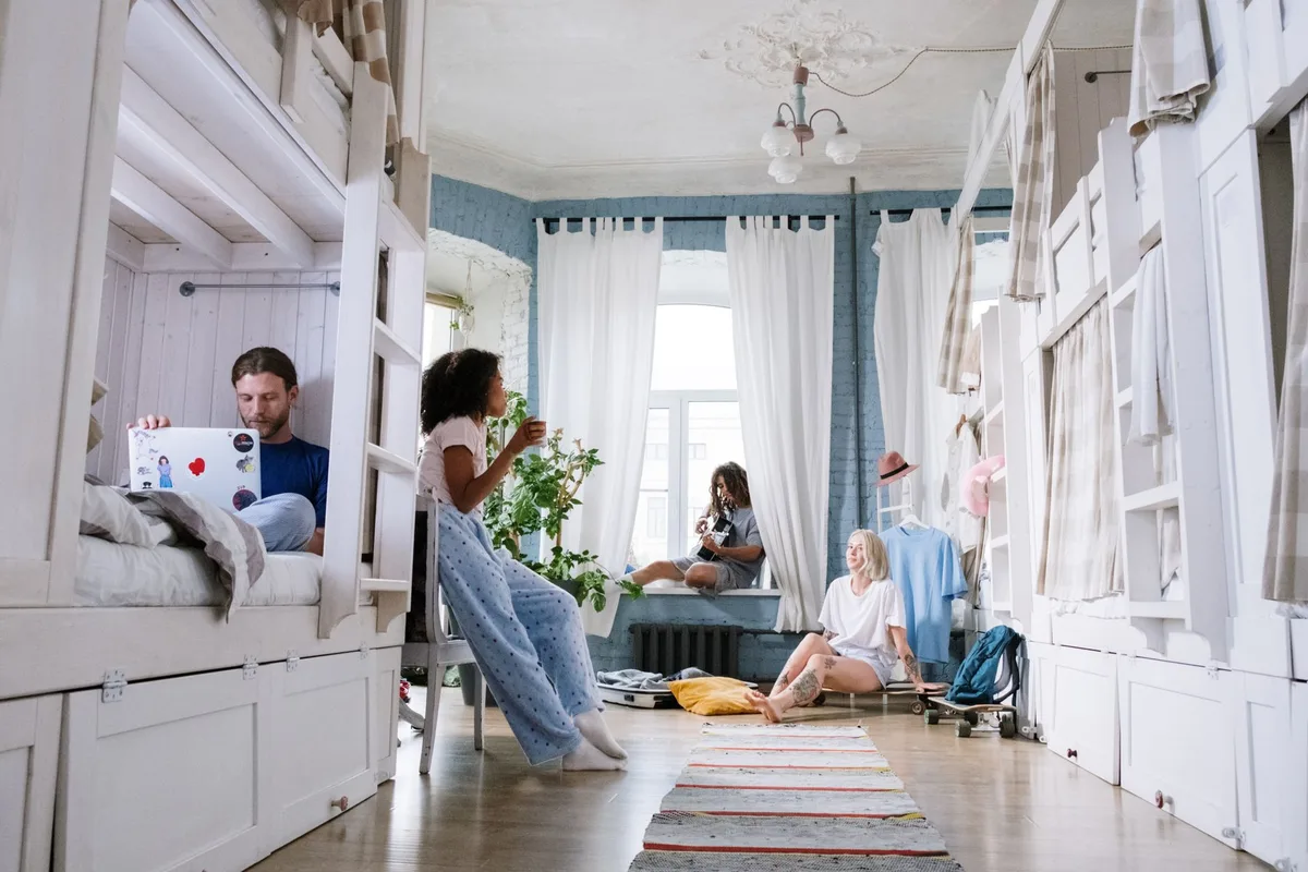 A cozy dorm room where friends relax, chat, and use laptops together