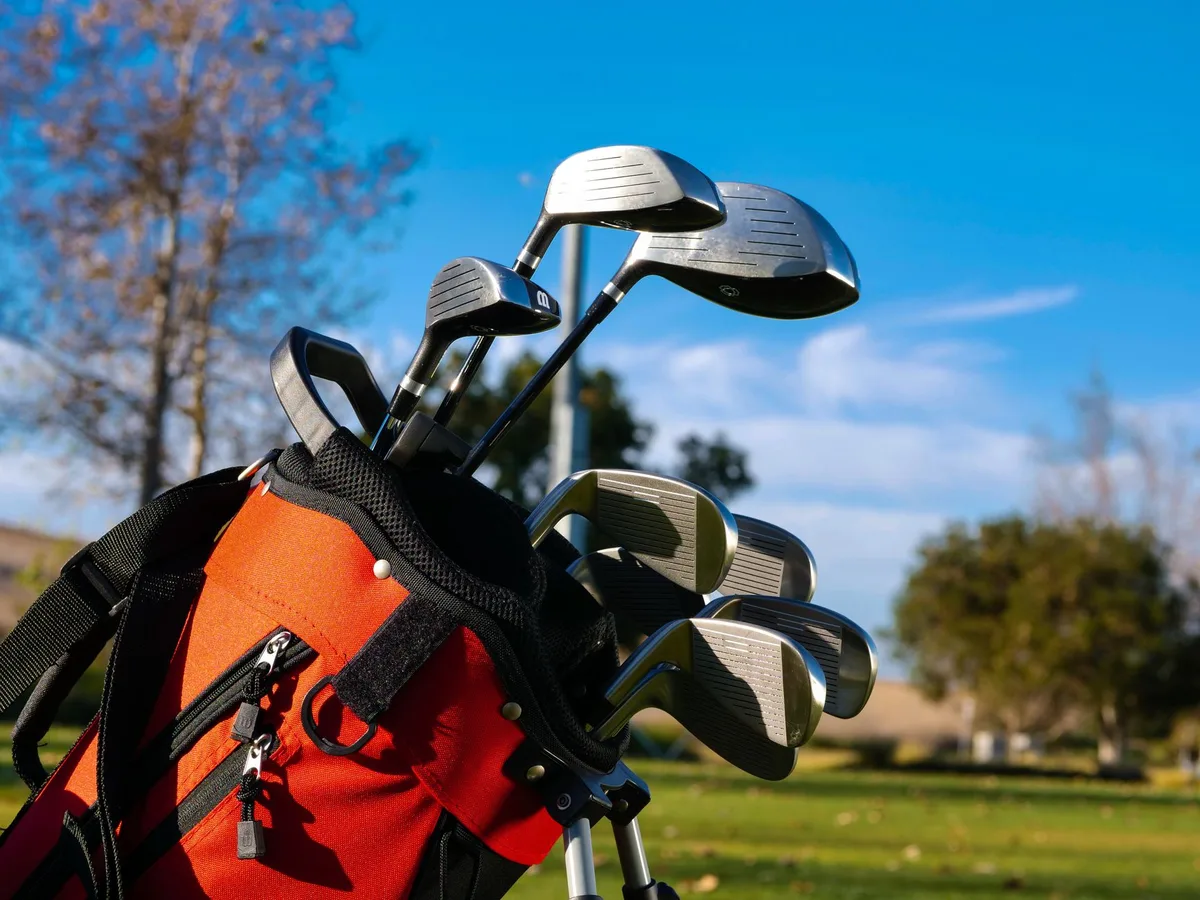 Set of golf clubs in leather golf bag on green grass